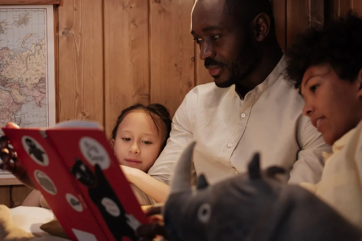 Father and children reading a storybook together in a cozy home setting.