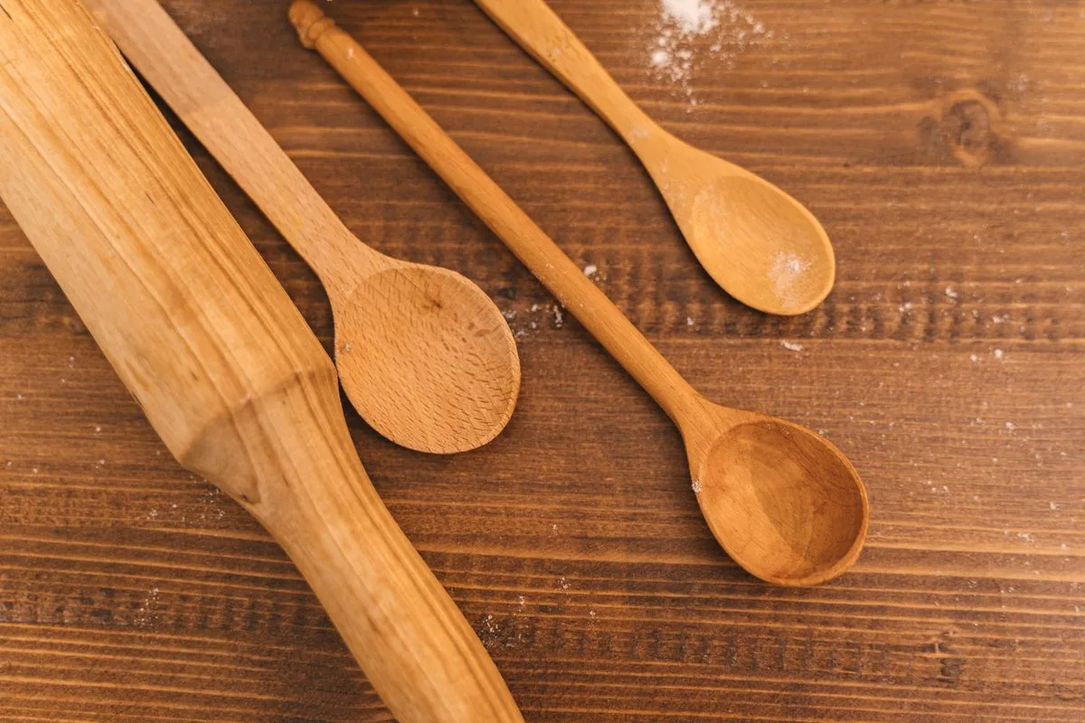 A collection of wooden kitchen utensils on a rustic wooden table.