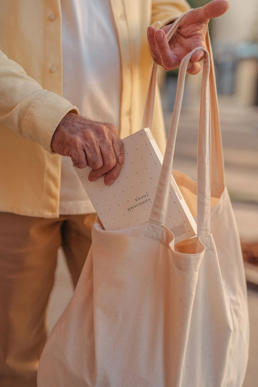 A senior placing a book into a tote bag.