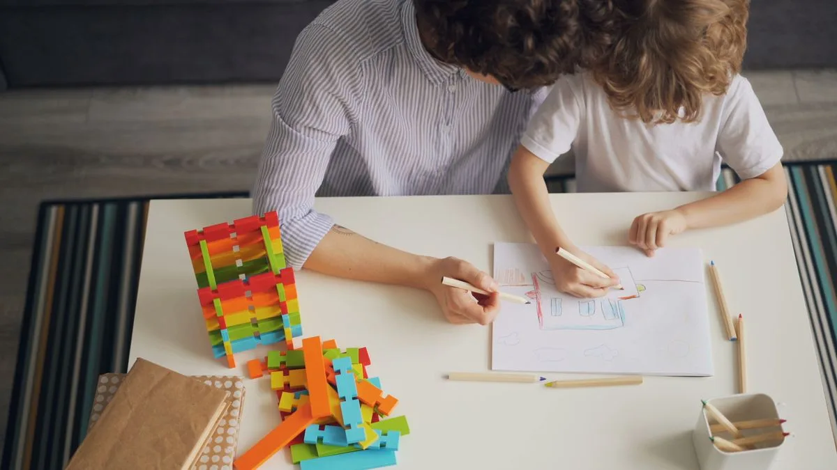 A mother and child drawing with coloured pencils at a table.