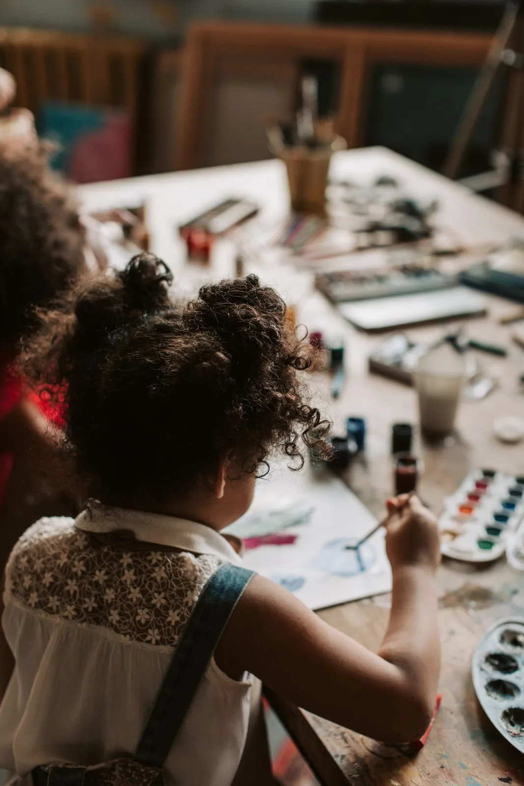 A child painting with watercolors at an indoor art studio.