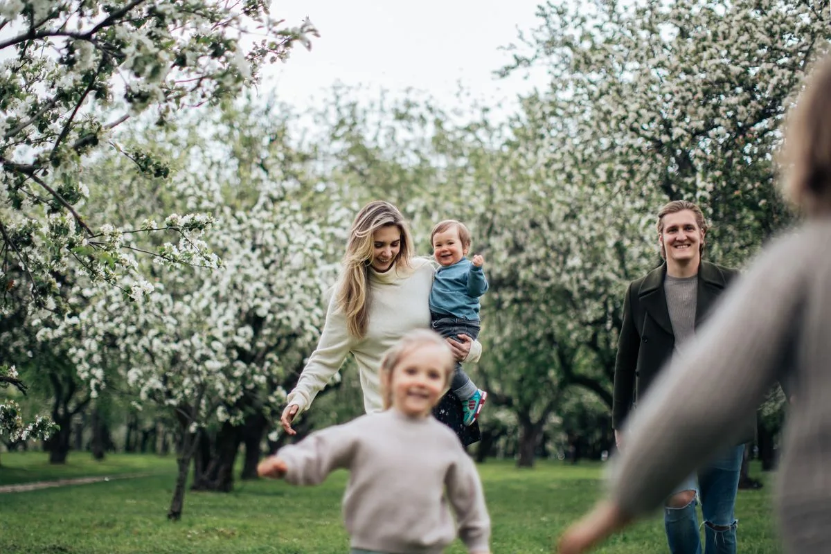 A joyful family enjoys a playful day outdoors amidst blossoming trees in spring.