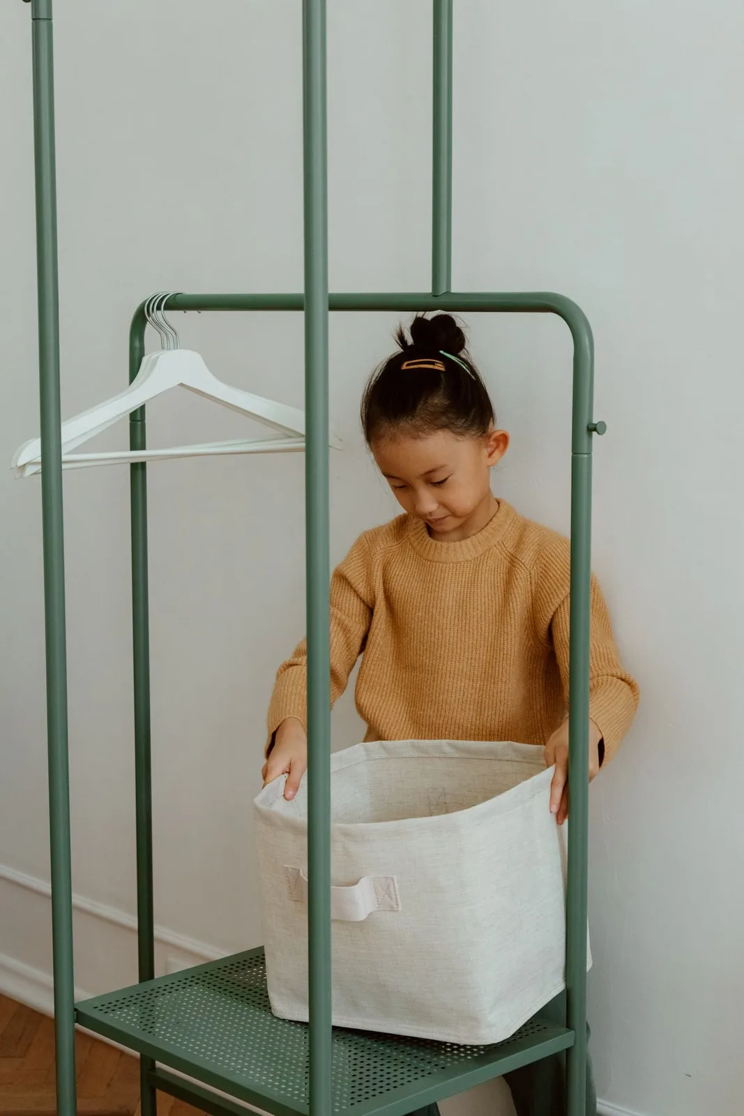 A young girl organizing items in a living room using a storage basket.