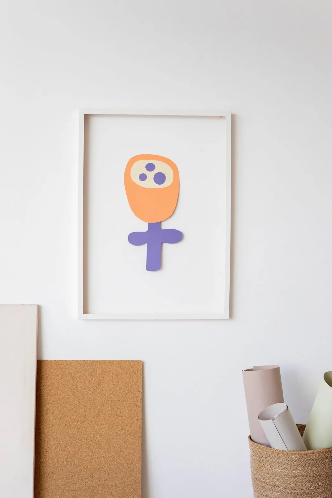Colorful child's craft art displayed in a frame on a minimalist wall.