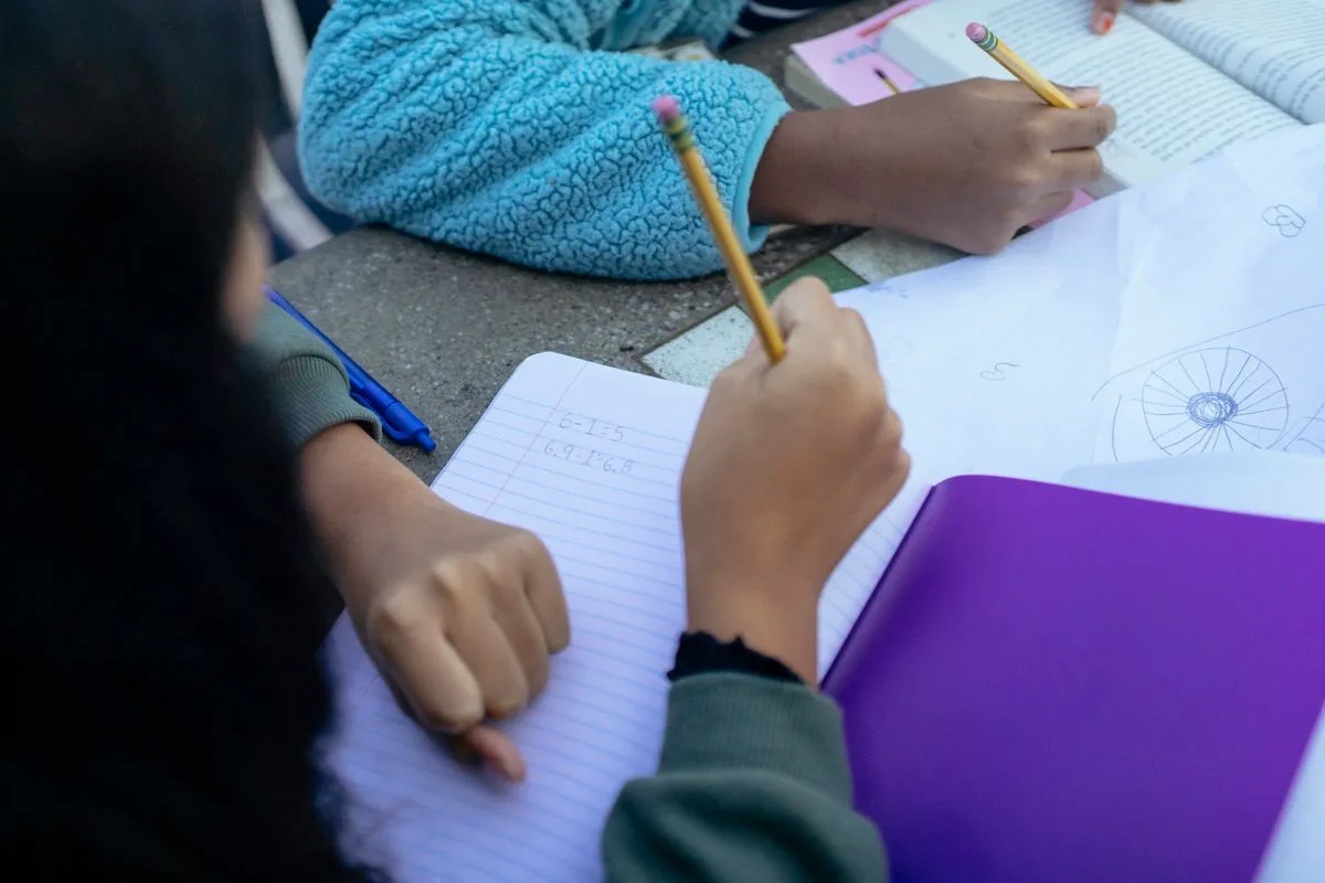 children sitting at table with pencils and doing homework together