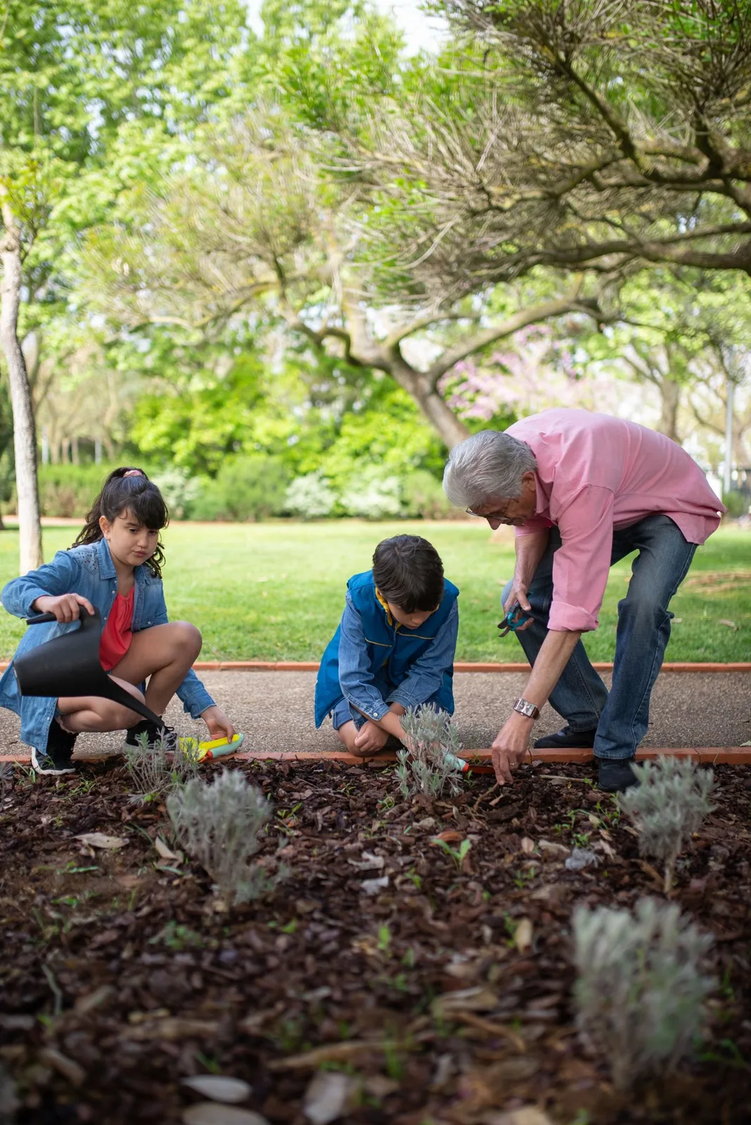 Grandfather and grandchildren tending to the garden together.
