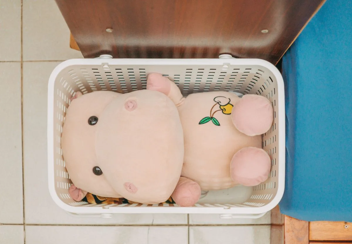 A cute plush hippo stuffed toy placed inside a white laundry basket.