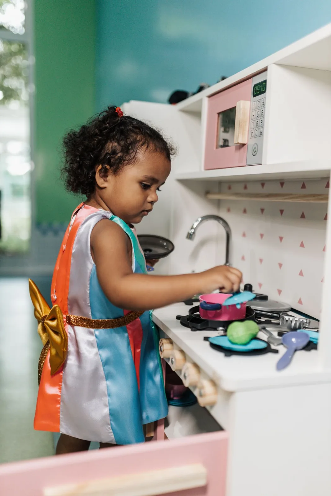 Adorable child focused on pretend play in a toy kitchen indoors.