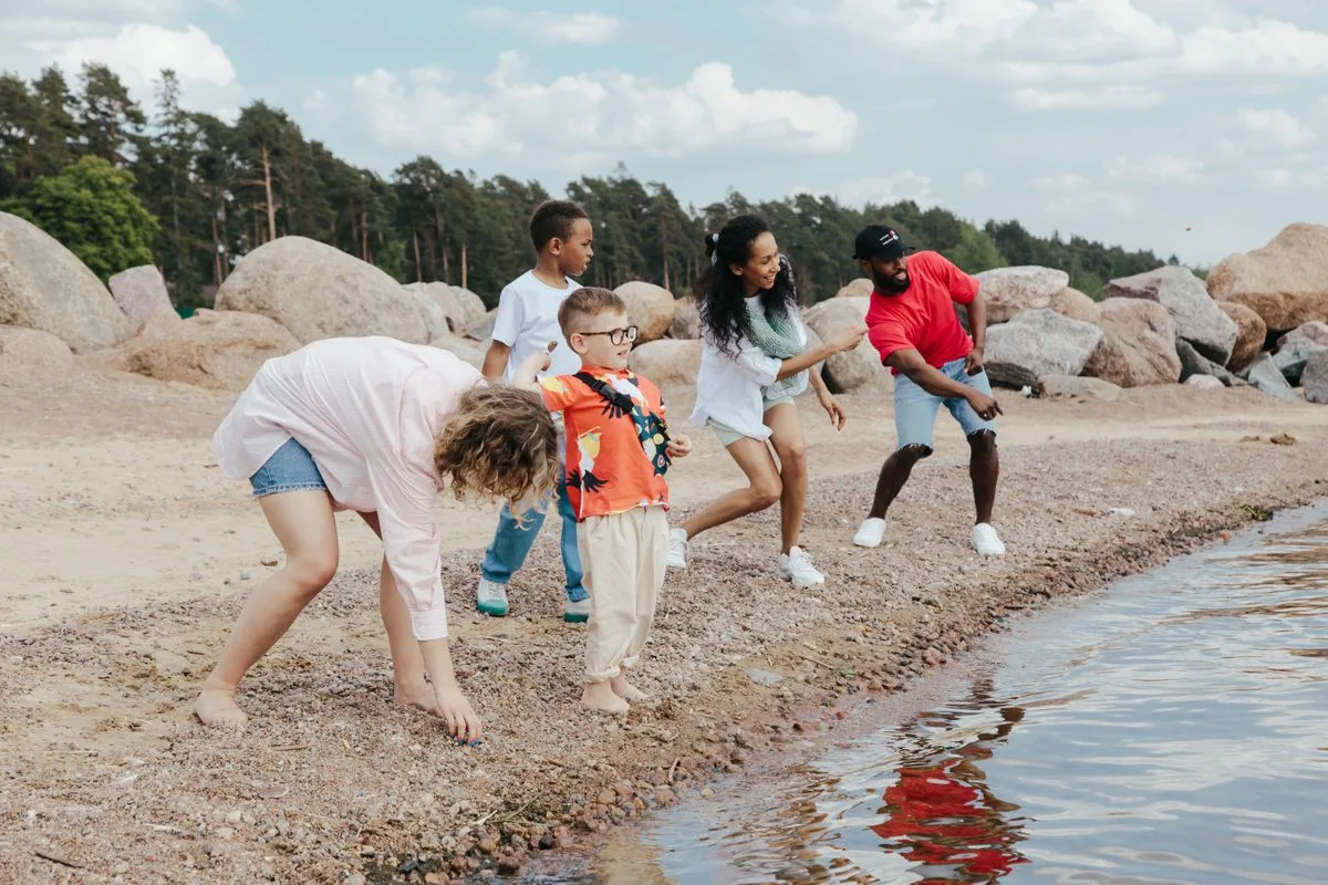 A diverse family having fun skipping stones on a scenic beach.